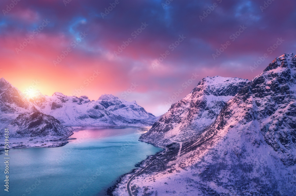 冬季日落时美丽的雪山、大海、道路和天空的鸟瞰图。罗弗特