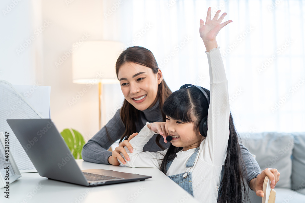 亚洲小女孩在家和妈妈一起学习在线课程。