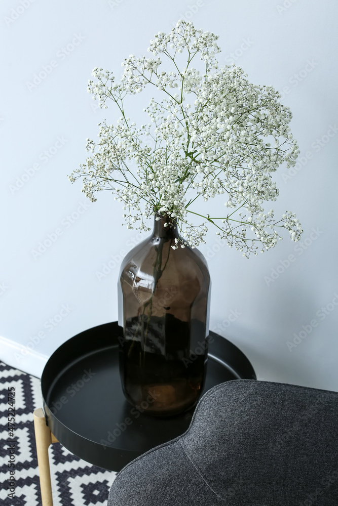 靠近灯光墙的桌子上放着一个开着吉普赛花的黑色花瓶