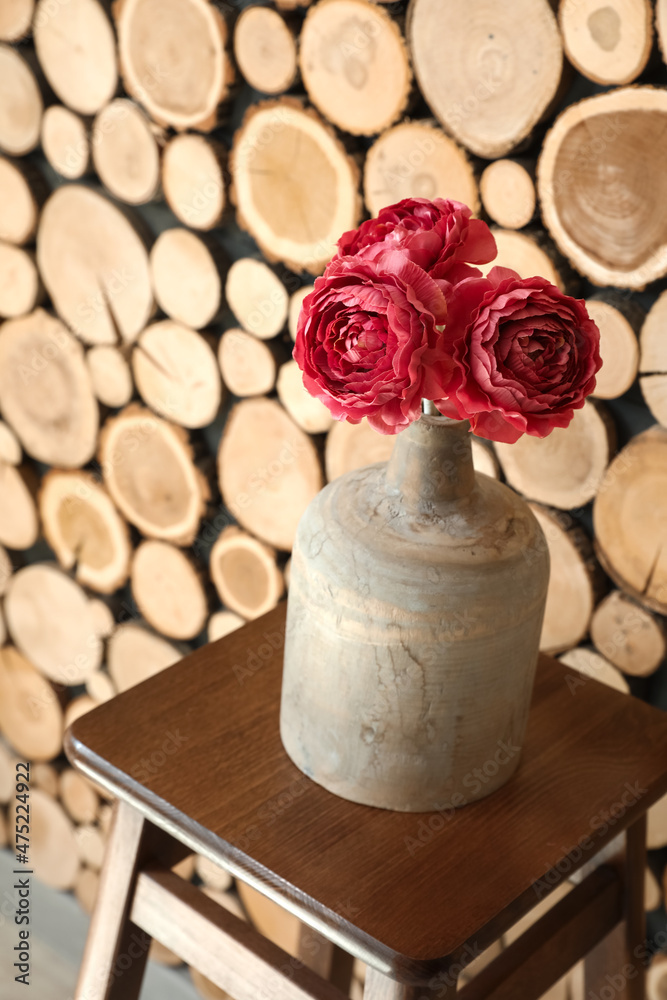 木墙附近的凳子上有漂亮花朵的花瓶