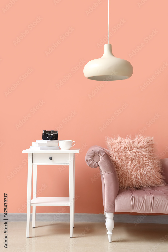 时尚舒适的扶手椅，靠近房间粉色墙壁的桌子