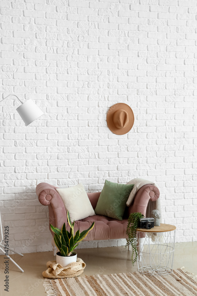 室内白色砖墙附近带有室内植物的时尚舒适扶手椅