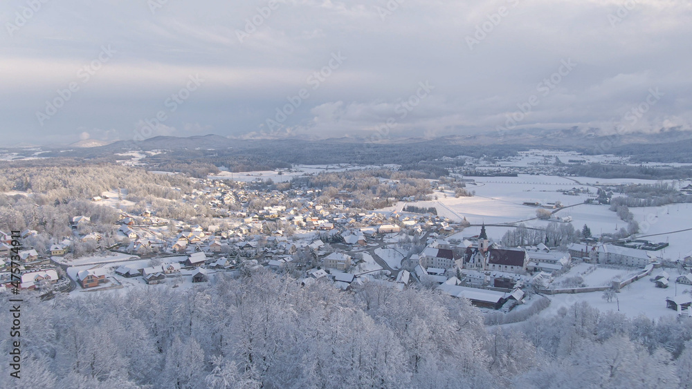空中：冬日清晨的阳光照亮了雪域山谷和郊区村庄。