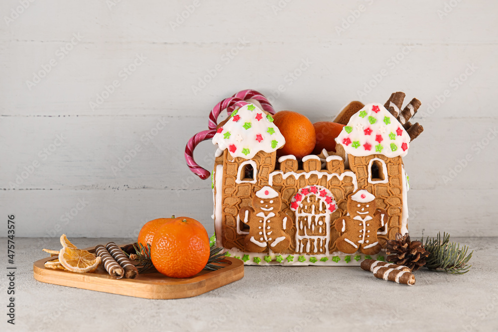 Beautiful gingerbread house, treats and tangerines on table