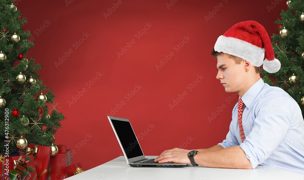 年轻的快乐男子独自在家庆祝圣诞节时通过笔记本电脑进行视频通话。