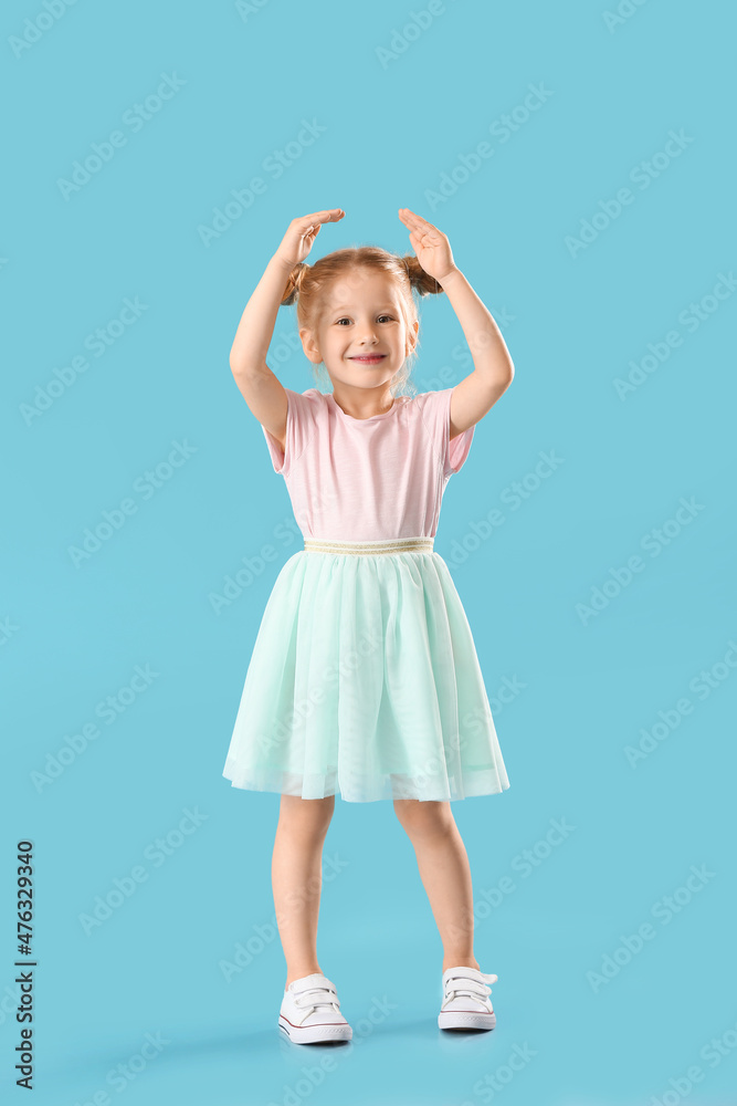 穿着裙子在蓝色背景下跳舞的可爱小女孩