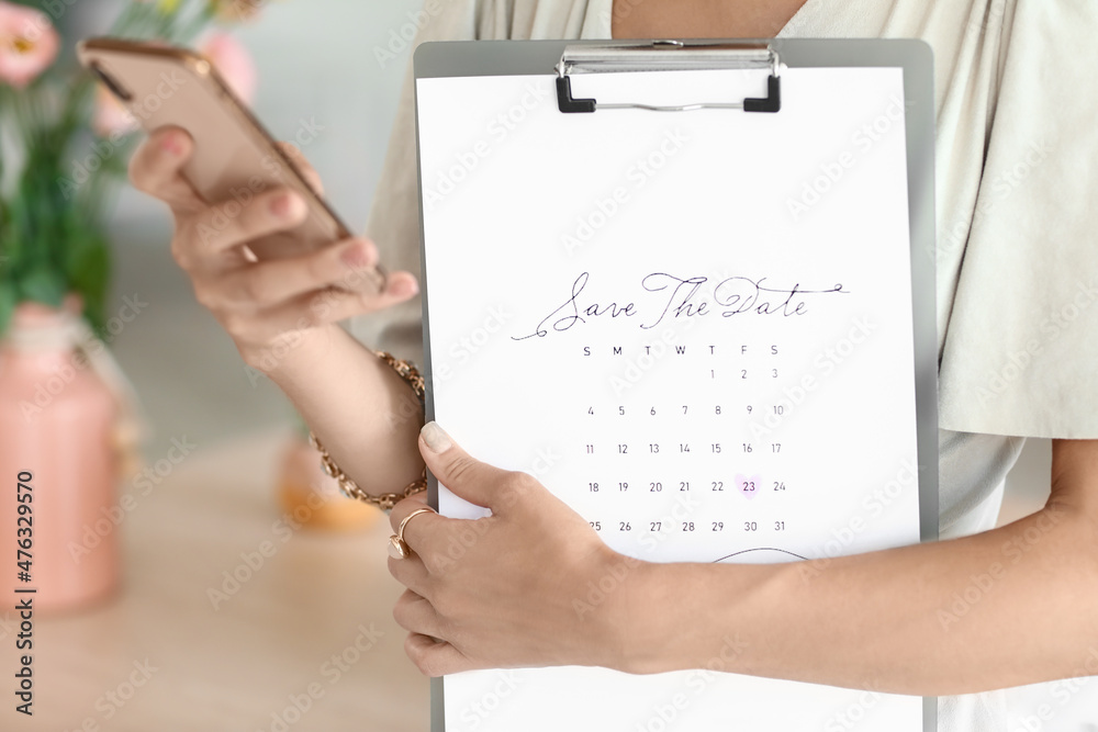 Female wedding planner with phone and Save the Date Announcement in office, closeup