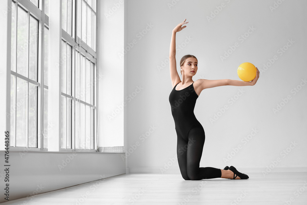 美丽的年轻女子在健身房做持球体操