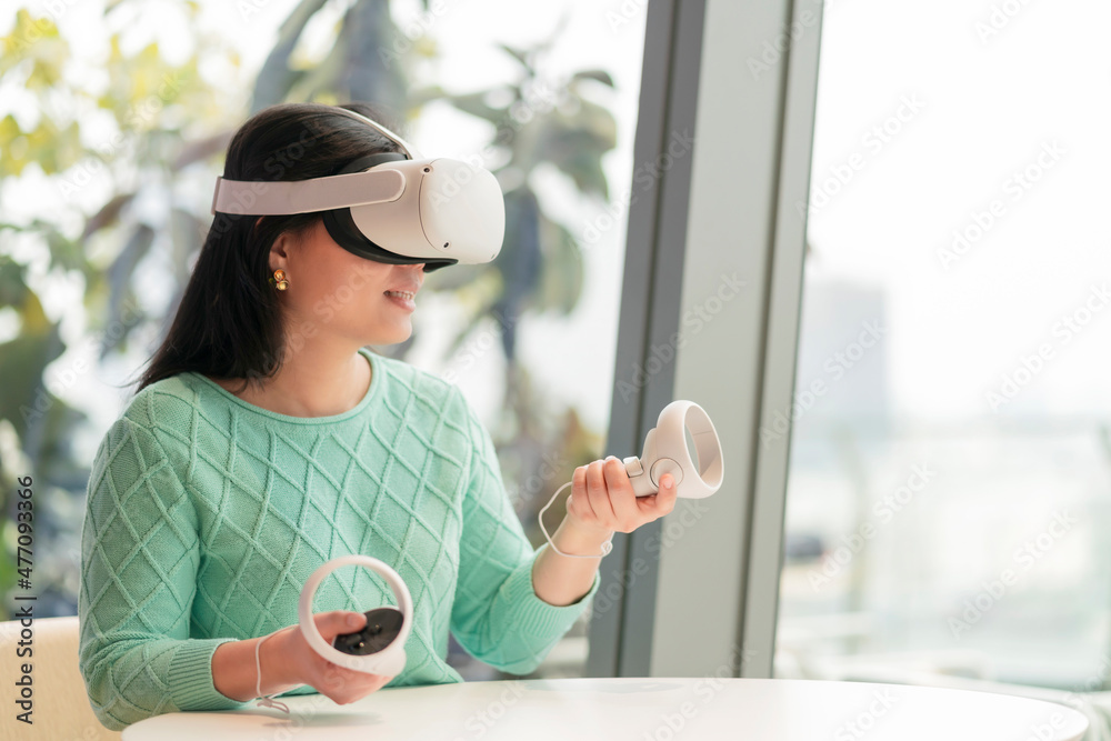 戴着虚拟现实增强现实眼镜的聪明迷人的亚洲女企业主享受