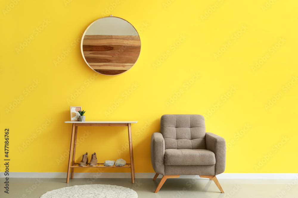 黄色墙壁附近的软扶手椅和带鞋支架