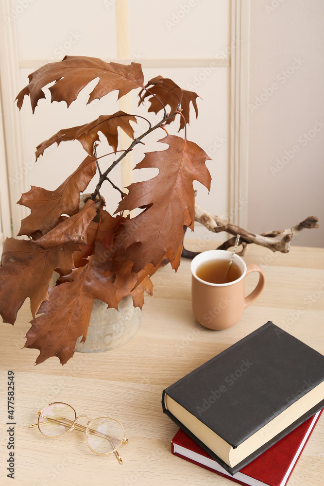 木桌上的秋枝、茶杯、书和眼镜