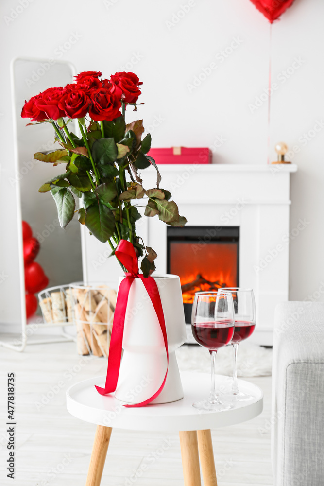 为情人节装饰的客厅桌子上摆着一杯葡萄酒和一个花瓶，花瓶上有美丽的花朵