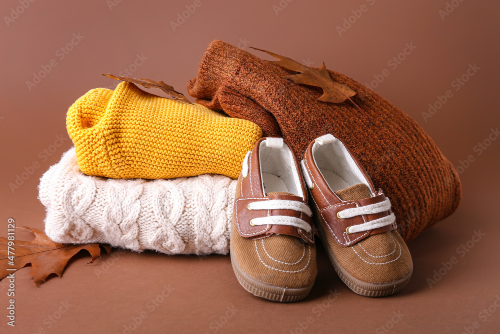 彩色背景上的一堆婴儿衣服、鞋子和秋叶