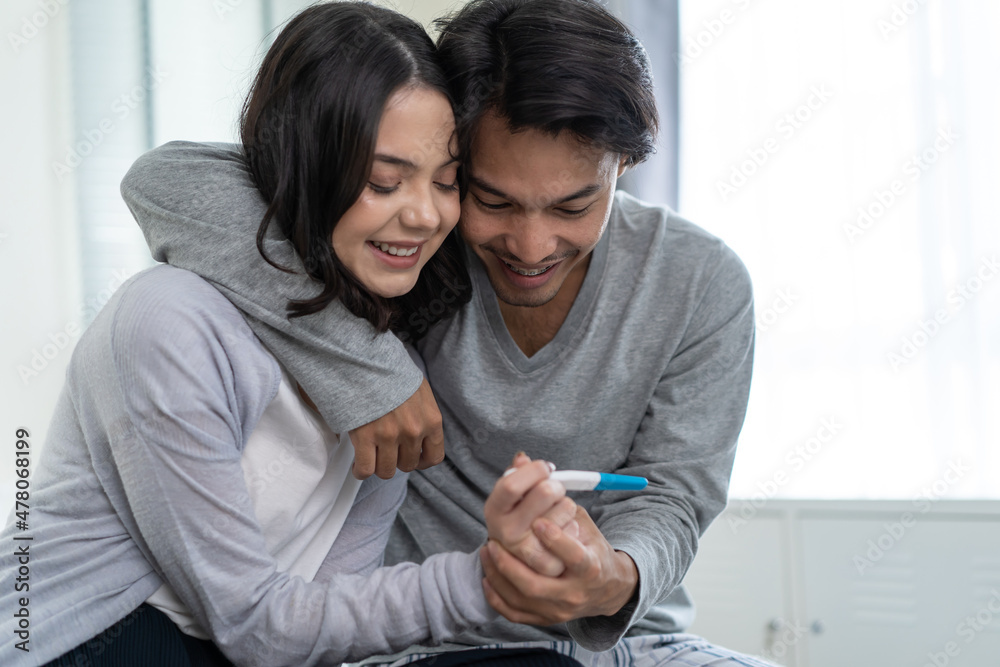 Asian young couple feeling happy after look at positive pregnancy test