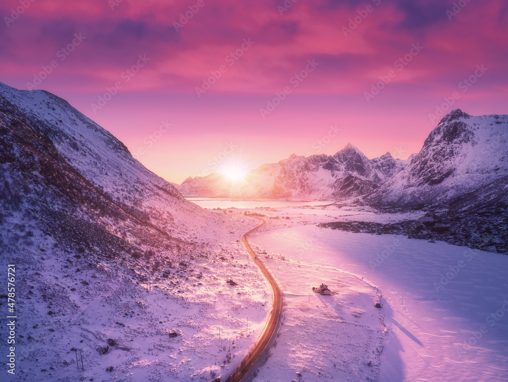 空中俯瞰美丽的雪山、道路、房屋和紫色的天空，冬天有粉色的云