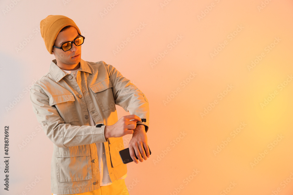 穿着时尚夹克、手机背景为彩色的年轻人