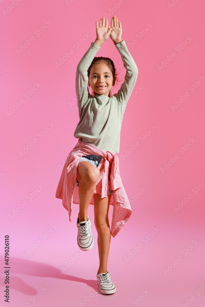 可爱的小女孩在粉色背景下跳舞