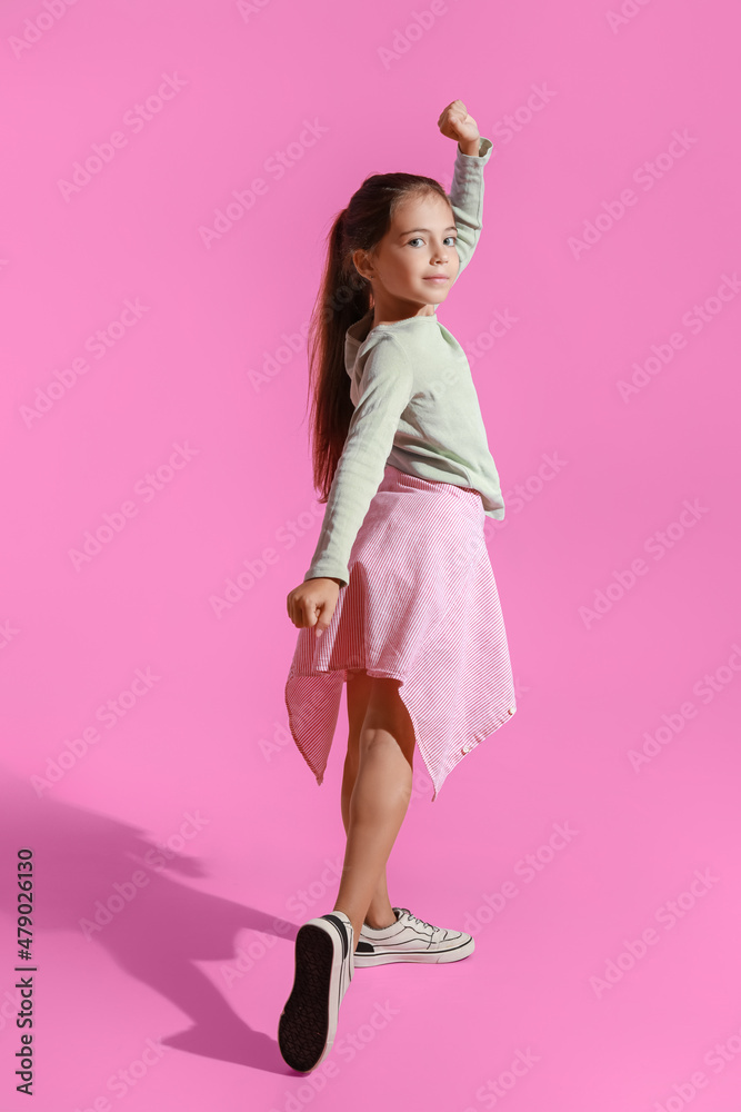 可爱的小女孩在粉色背景下跳舞