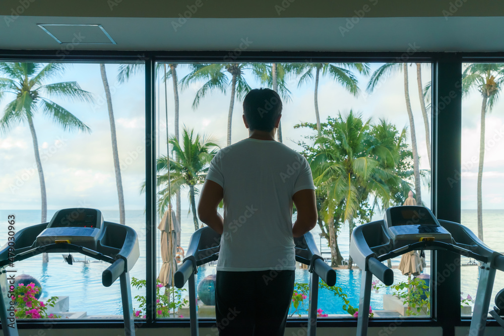 亚洲男子早上在度假村健身中心的跑步机上锻炼。