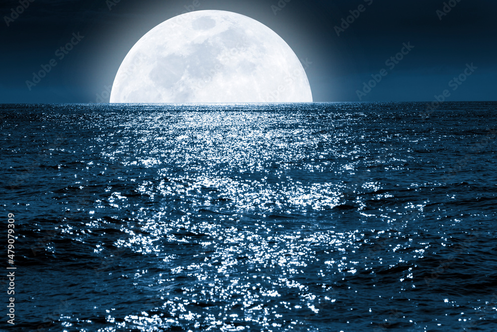 非常大的满月在平静的海洋中升起。