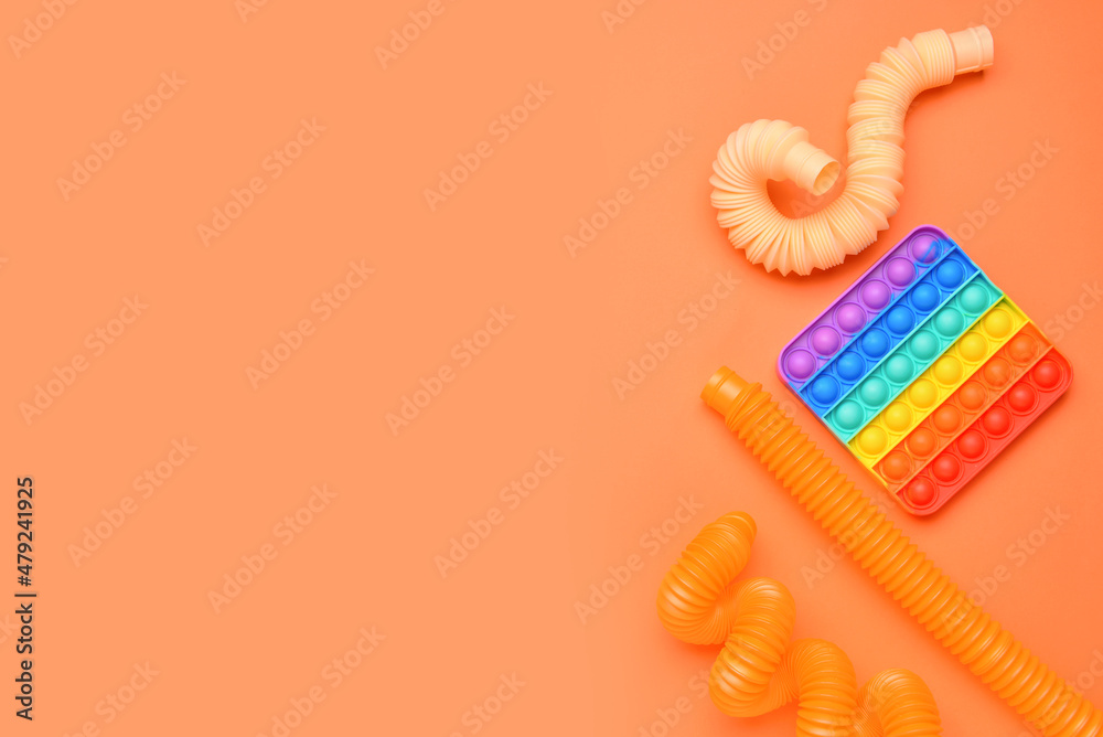 橙色背景下的彩色Pop Tubes和Pop-it坐立不安玩具