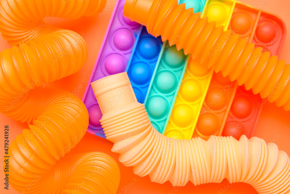 橙色背景的彩色Pop Tubes和Pop-it fidget玩具
