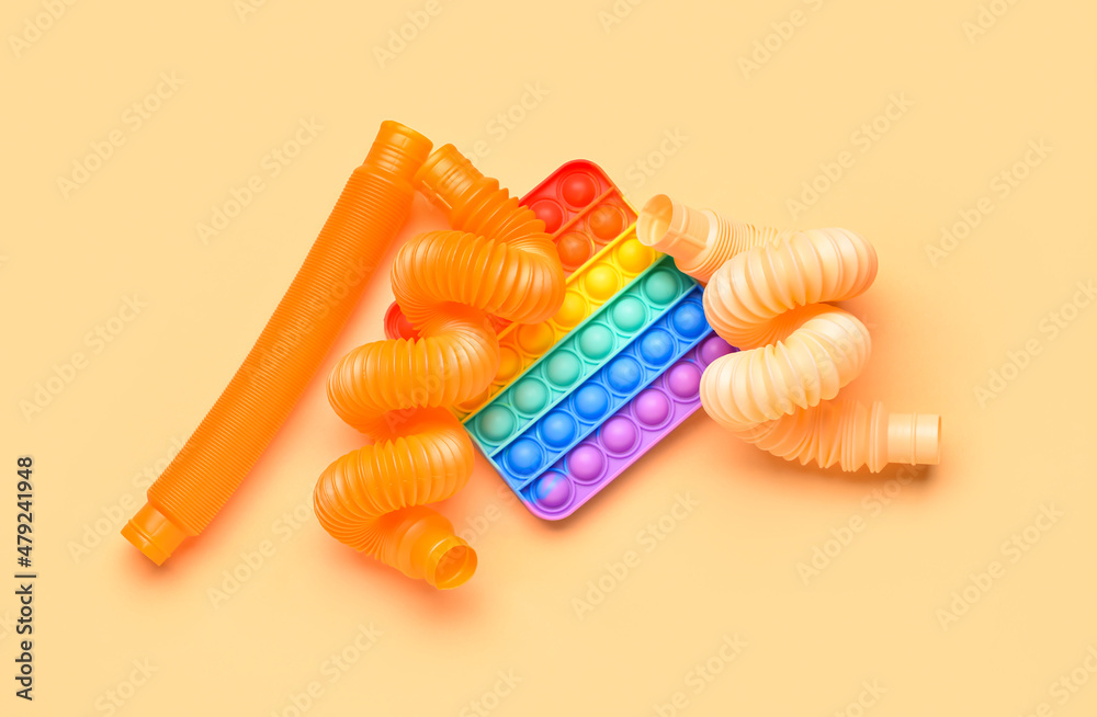 米色背景下的彩色流行管和流行玩具