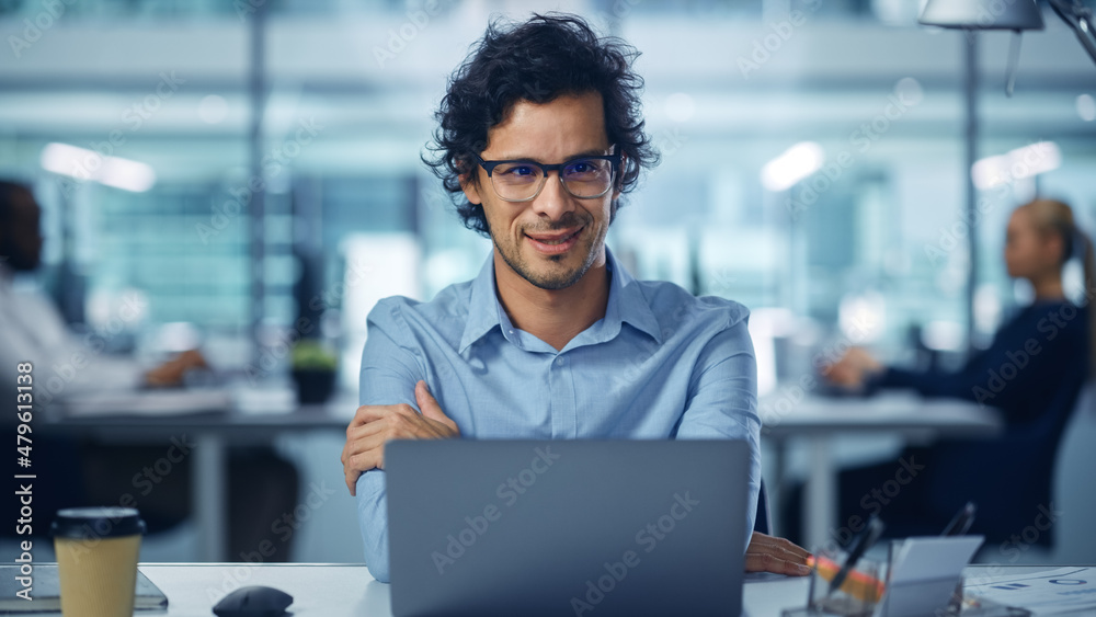 现代办公室商人在电脑上工作，微笑，看着相机。成功La的肖像