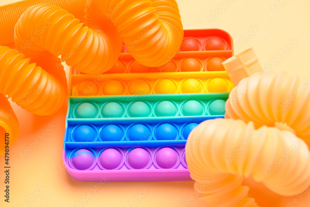 米色背景下的彩色流行管和流行玩具