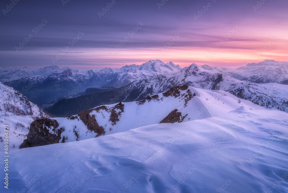 Snow covered mountains and colorful purple sky with clouds at sunset in winter. Beautiful wintry lan