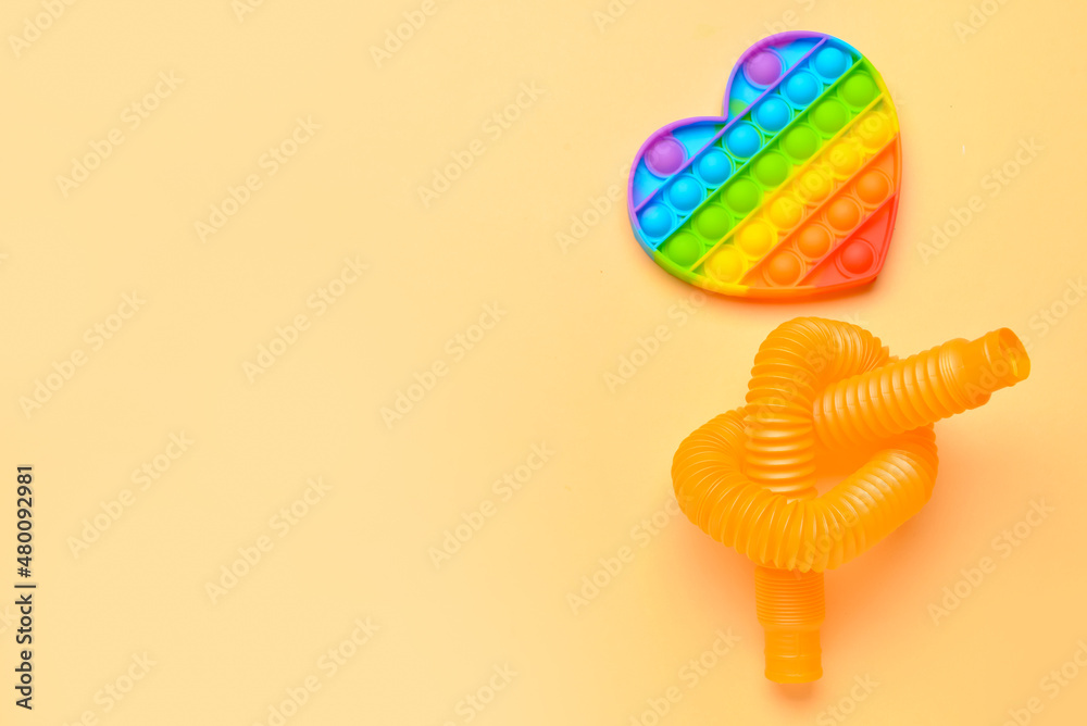 米色背景下的彩色Pop Tube和Pop-it坐立不安的玩具