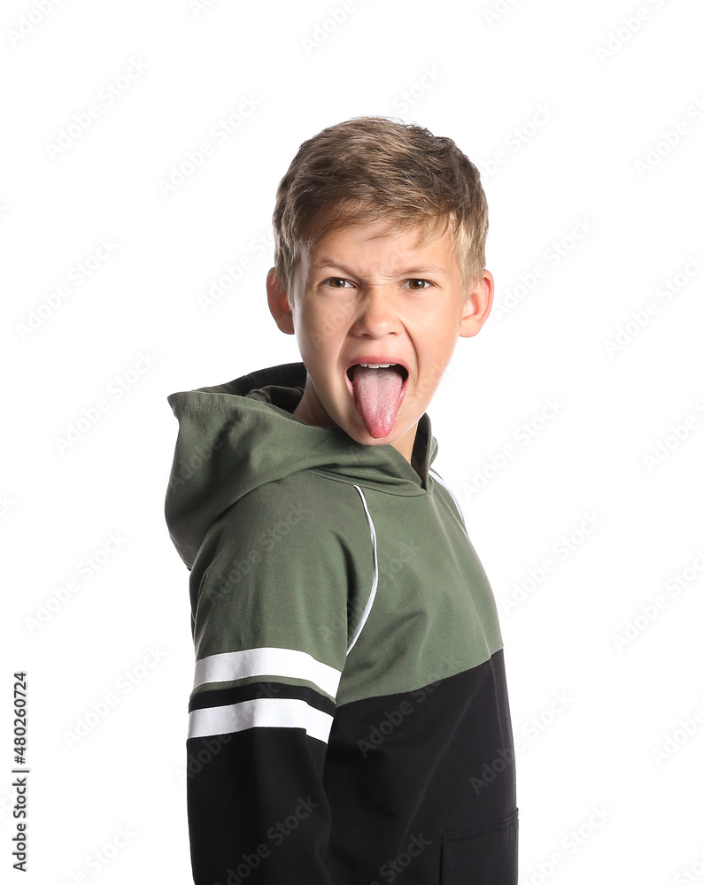Angry little boy in hoodie showing tongue on white background