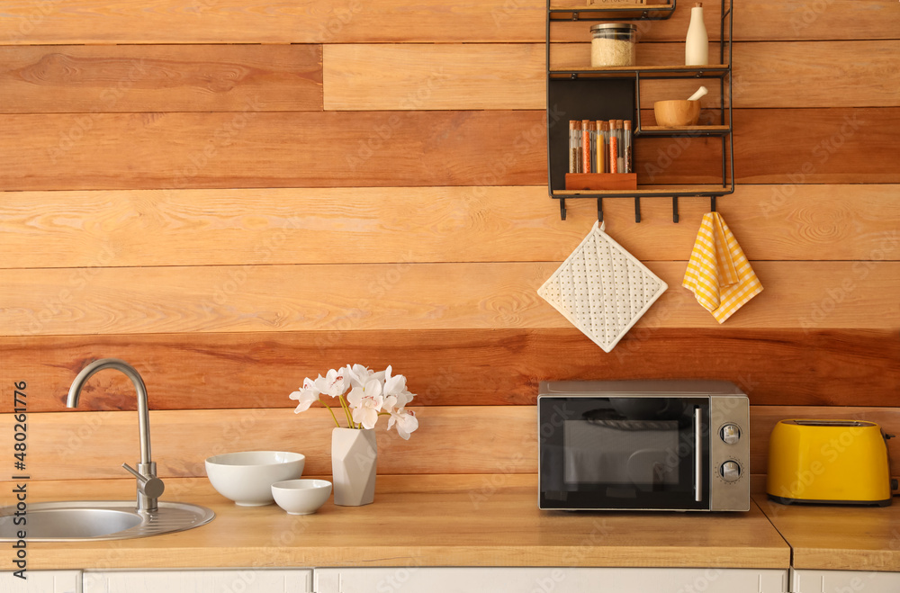 木质墙壁附近有不同炊具和微波炉的厨房柜台