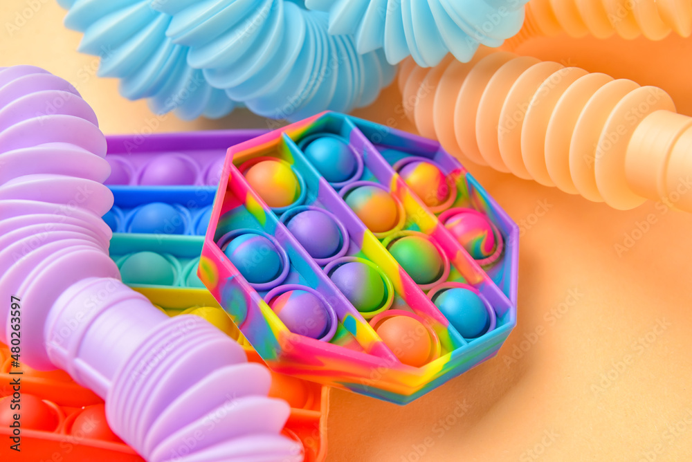 米色背景下的彩色Pop Tubes和Pop-it坐立不安的玩具