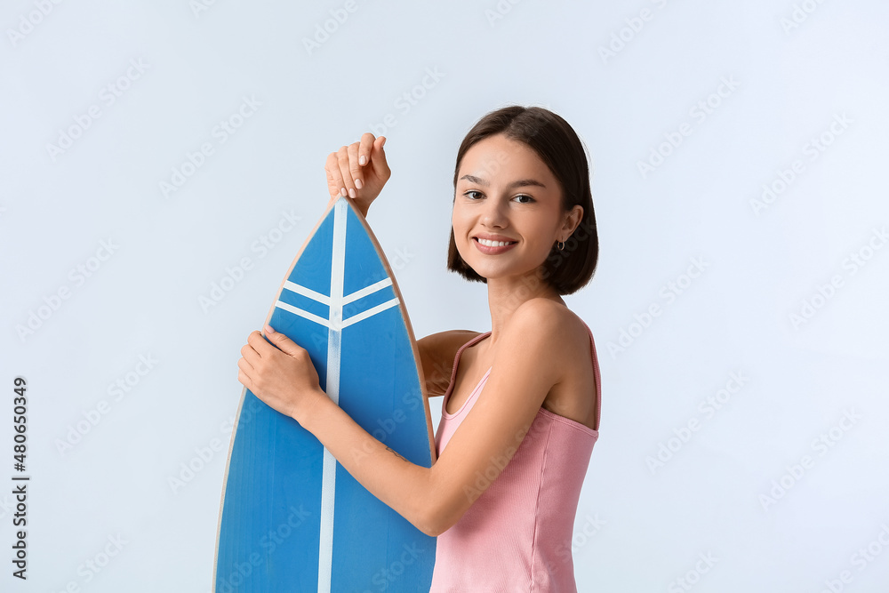 漂亮的年轻女子，浅色背景上有冲浪板