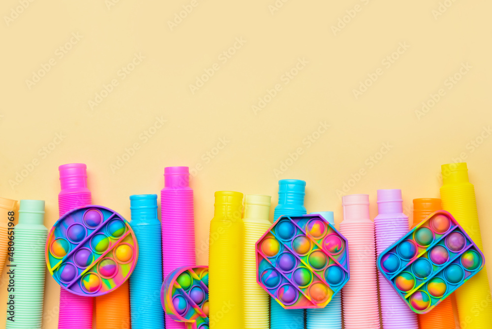 黄色背景上的彩色Pop Tubes和Pop-it fidget玩具