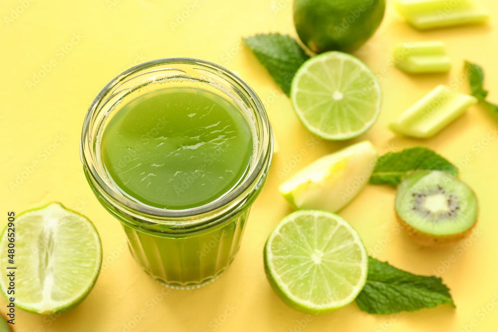 一杯健康的绿色果汁和黄色背景的新鲜水果