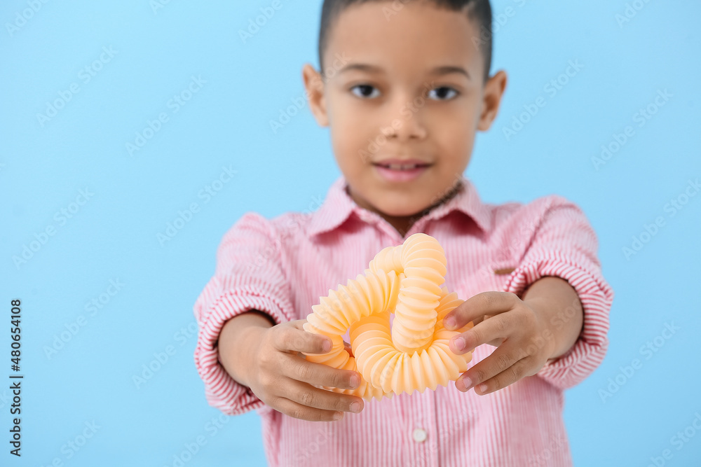 Little African-American boy with orange Pop Tube on blue background, closeup
