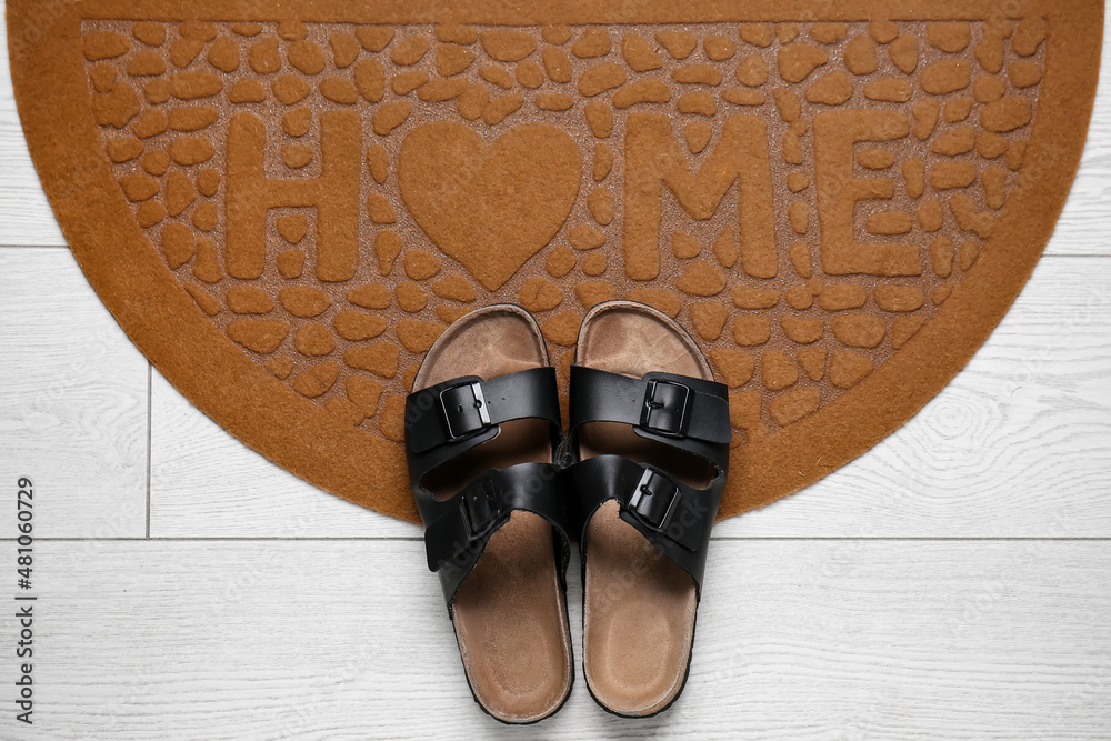 Brown door mat with shoes on white wooden floor