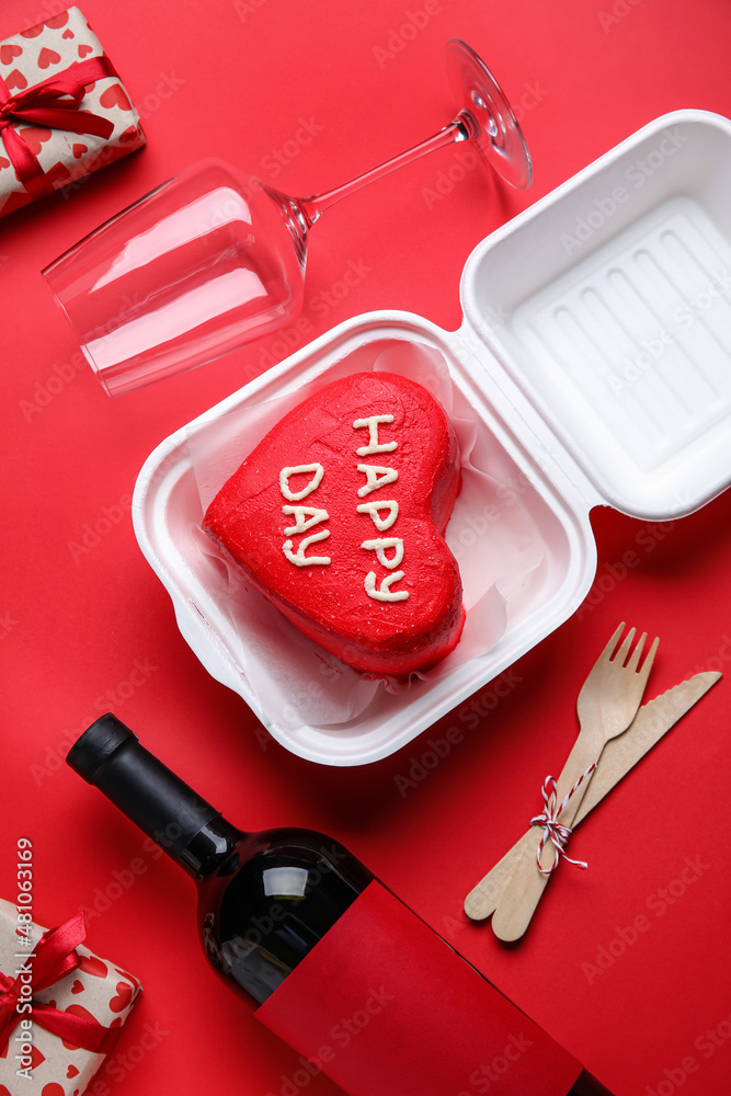 Plastic lunch box with tasty bento cake, glass and bottle of wine for Valentines Day on red backgro