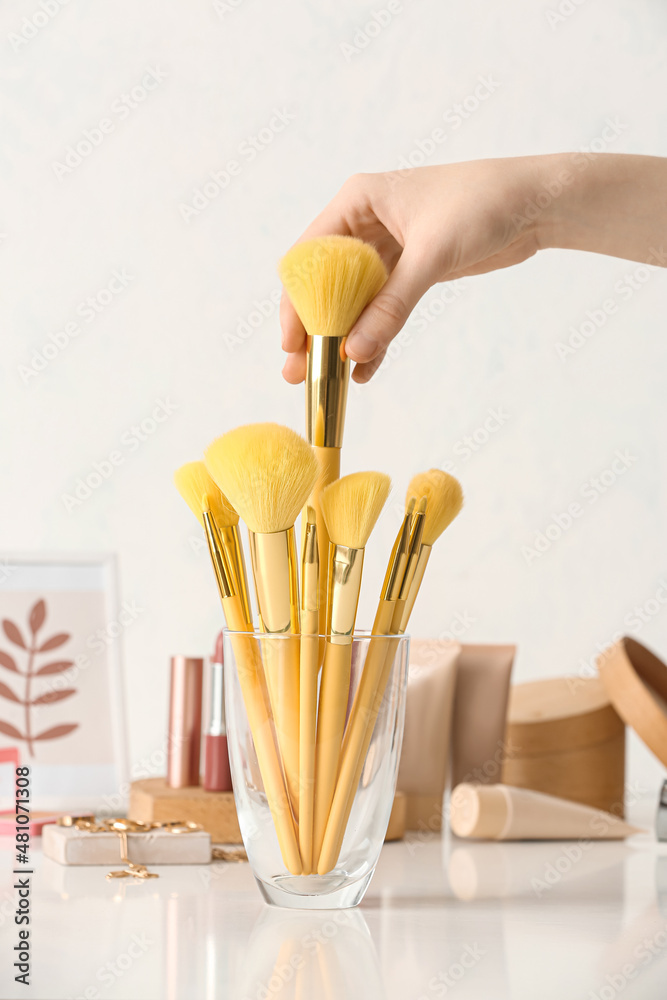 Woman with set of makeup brushes on table