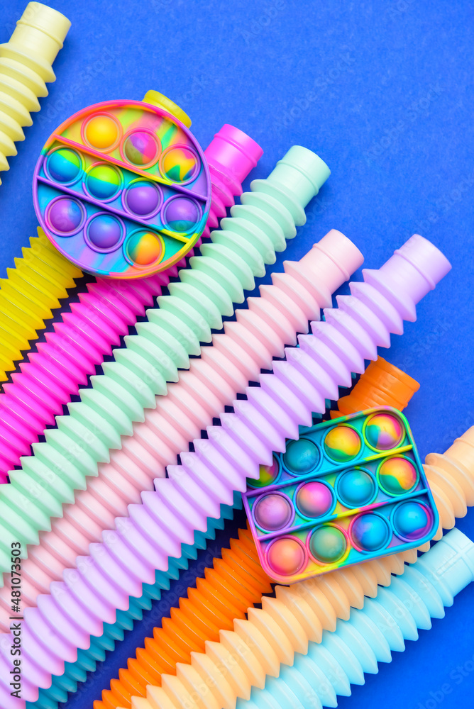 Colorful Pop Tubes and Pop it fidget toys on blue background