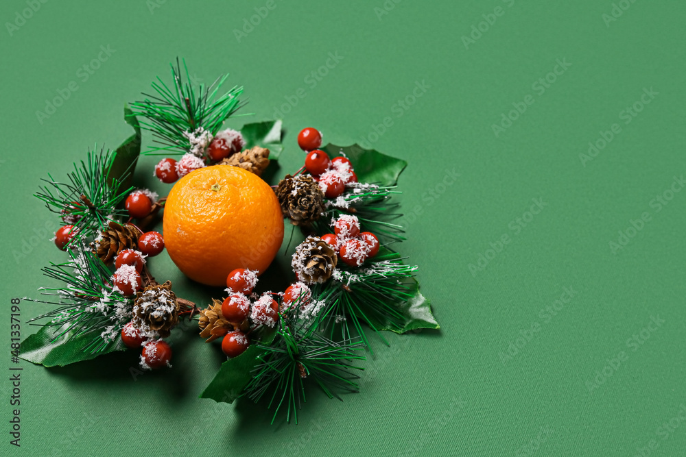 绿色背景下的圣诞花环和成熟蜜橘
