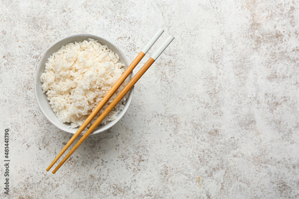 碗里有美味的煮米饭和筷子，背景是浅色的