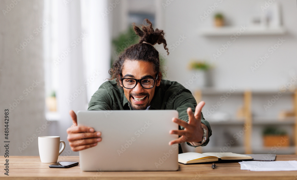 收到工作邀请后，看着笔记本电脑屏幕感到兴奋的非洲裔美国人欣喜若狂