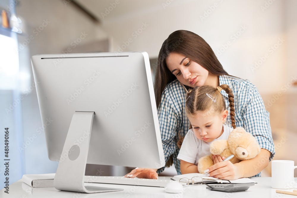 美丽的年轻母亲带着被宠坏的孩子在家里用电脑工作。妈妈或老师和我