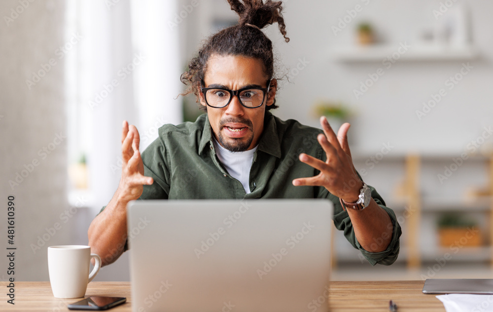 愤怒的年轻非洲裔美国人看着笔记本电脑，感到网络连接缓慢压力重重