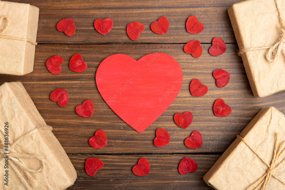 Valentines Day greetings concept. Little red wooden crafted hearts and gift boxes on the wooden bac