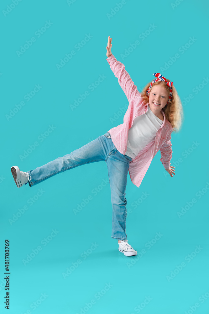 身穿条纹衬衫的红头发小女孩在蓝色背景下跳舞