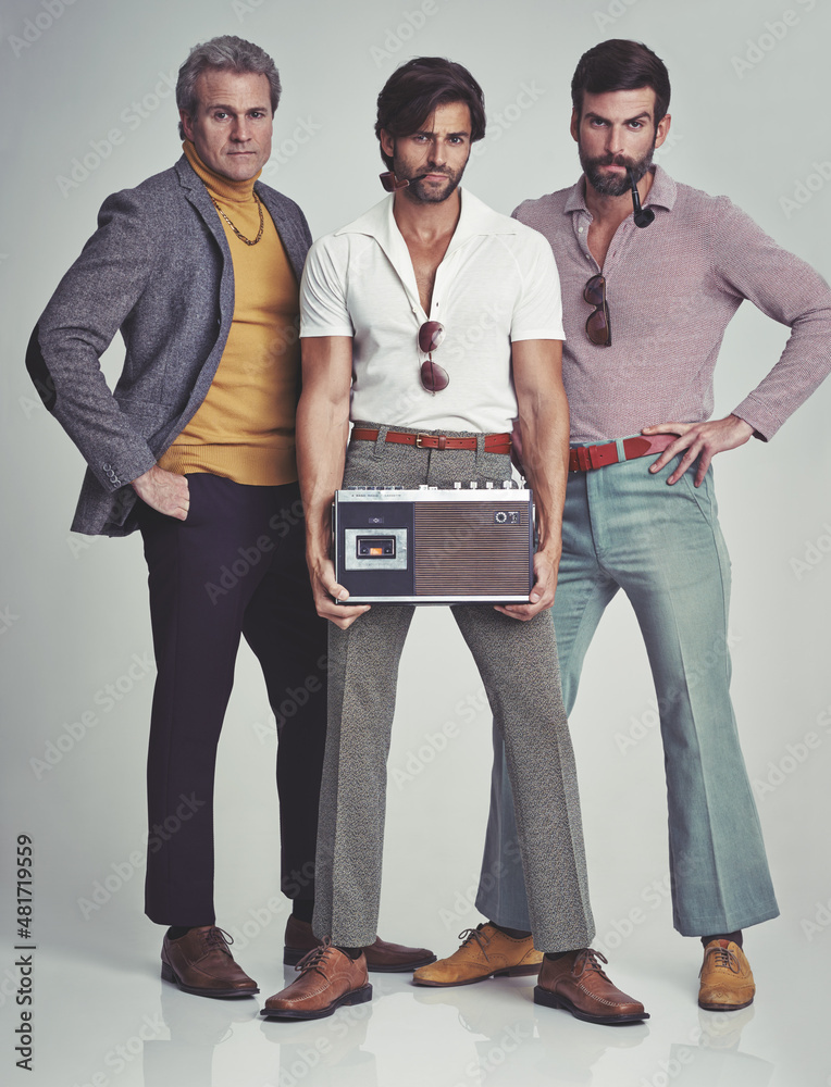 Ready to kick it retro style. A studio shot of three men clad in retro 70s wear holding a cassette p